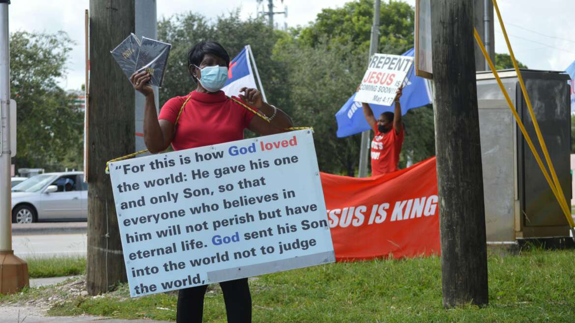 Woman in Medical Mask and Board with Script on Street